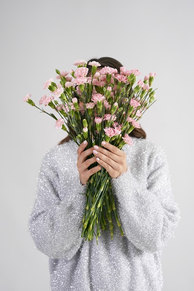 Mujer escondida detrás de un ramo de flores