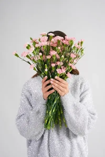 Mujer escondida detrás de un ramo de flores